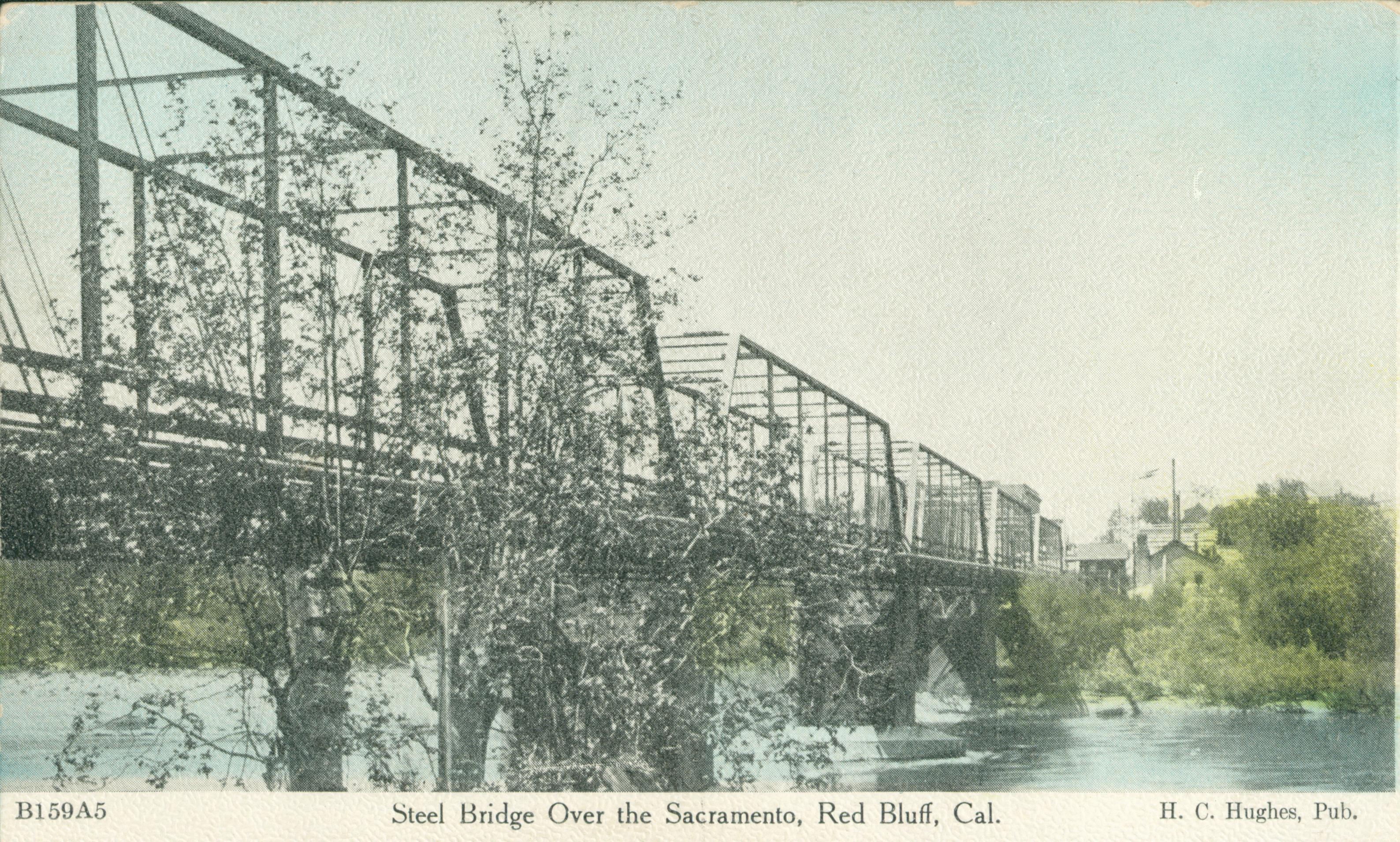Shows a steel bridge spanning a river with one shoreline in the background